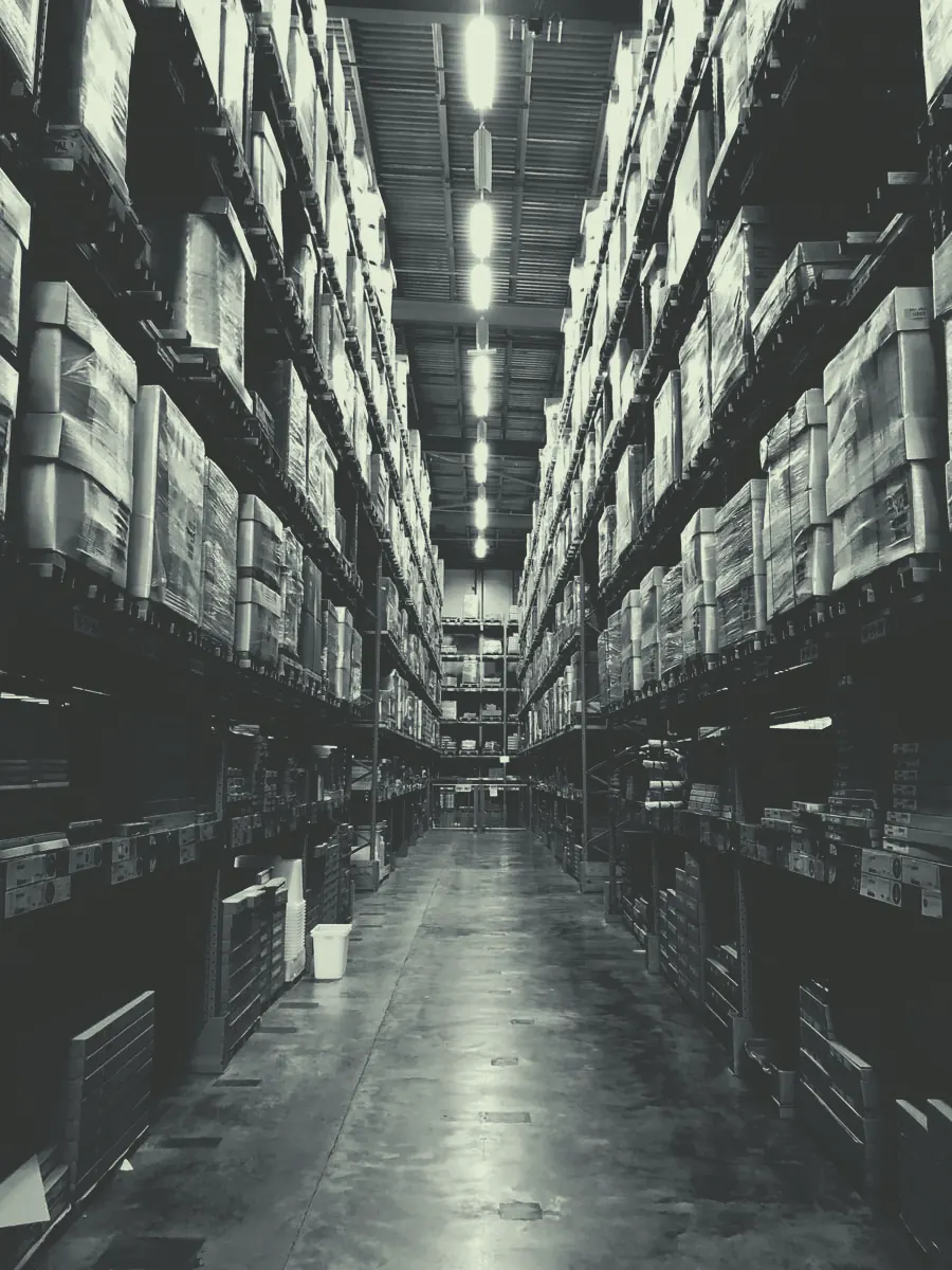 A fulfilment warehouse aisle stacked to the ceiling with palletised stock.